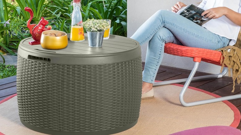 A person sits on a deck next to a green storage ottoman