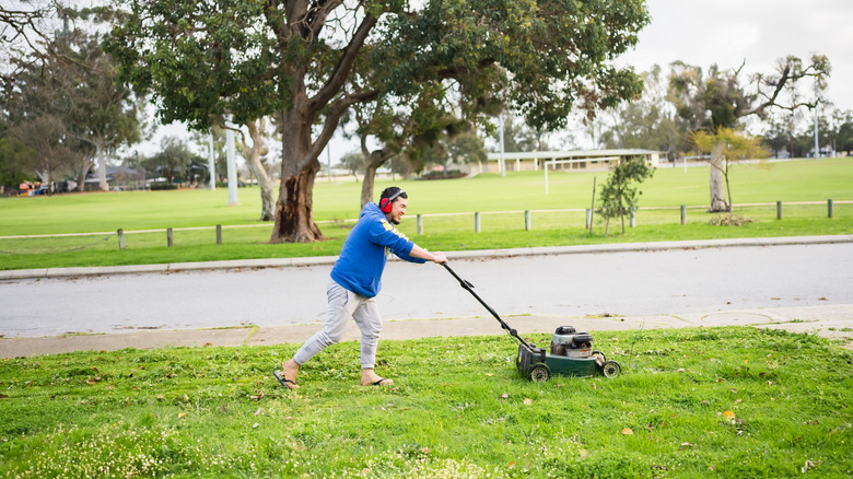 Man pushing a lawn mower.