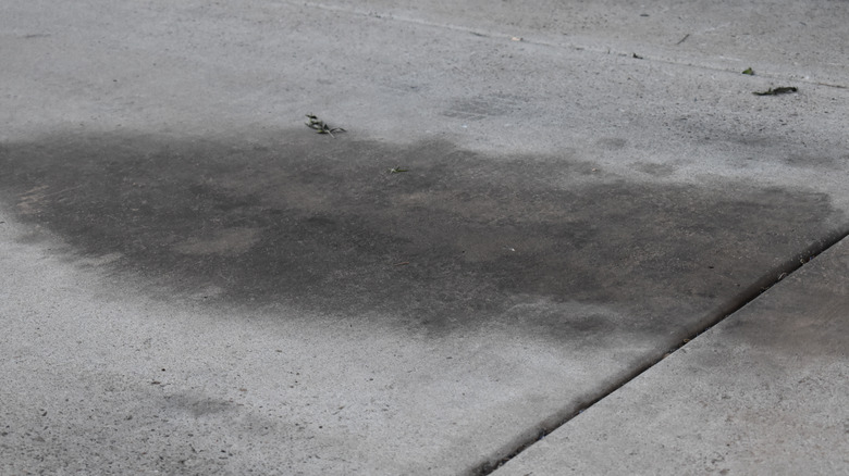 A dried oil stain sitting on a concrete driveway