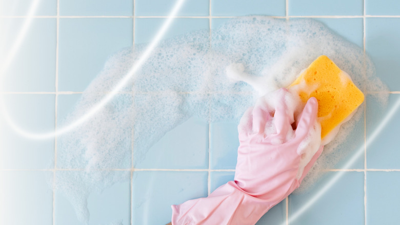 Gloved hand holding a sponge scrubbing with a trail of bubbles