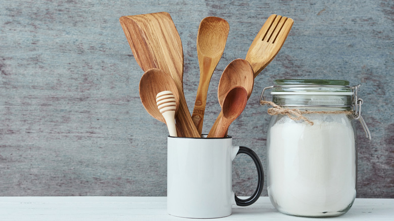 Wooden cooking utensils in a white mug on kitchen counter