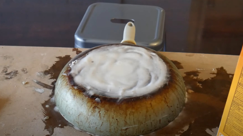 A person scrubbing pots and pans at a kitchen sink.