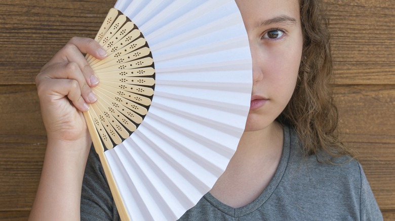 Girl holding fan in front of her face