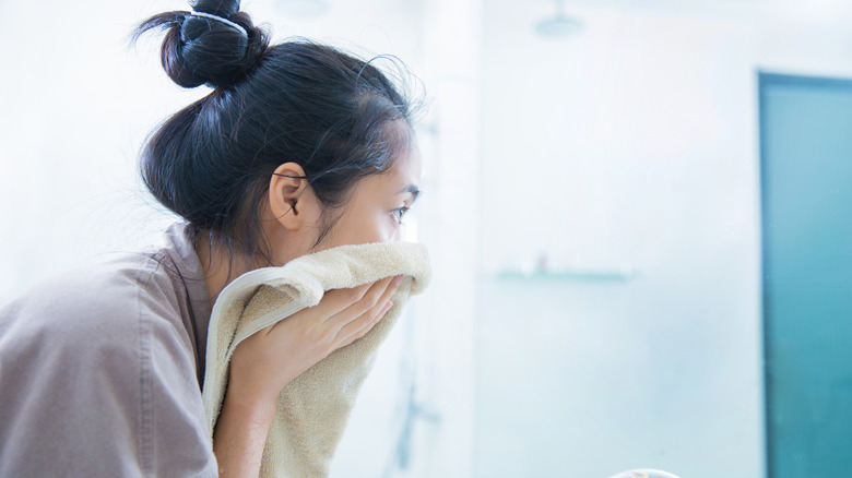Woman wiping her face n a bathroom