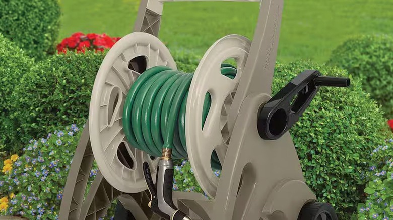 Rubber garden hose with nozzle on portable cart