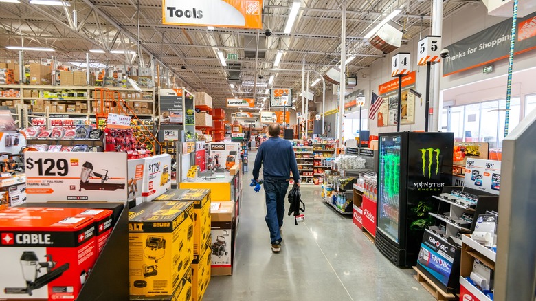 Man walking past the tool sectiion in a Home Depot store