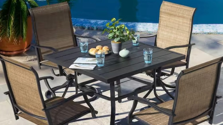 Four fabric and steel lawn chairs arranged around a steel table