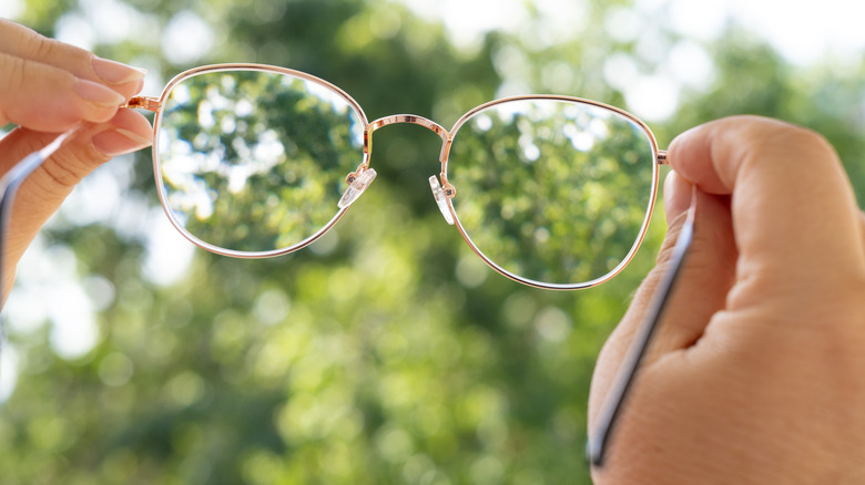A person's hands are holding up a pair of eyeglasses