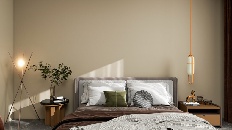 A beige-brown bedroom wall with an upholstered bed frame, side tables, and two lamps