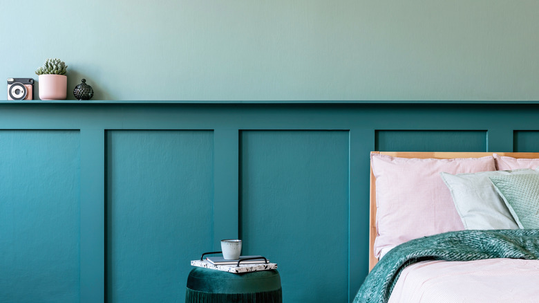 A bed against a blue-green wall with trim detailing