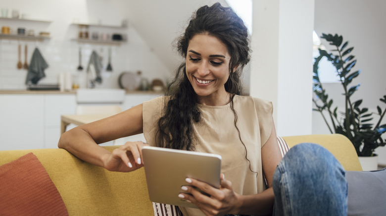 Woman sitting on a yellow couch using a tablet
