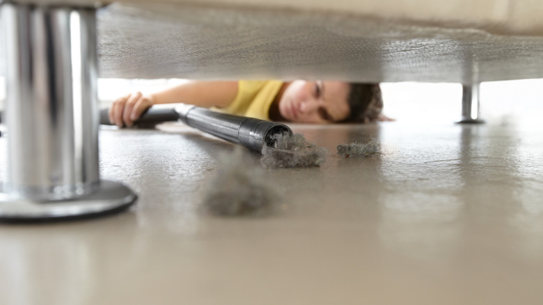Woman vacuuming under a sofa