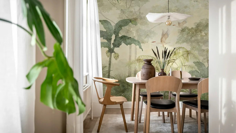 A neutral dining room features a bold palm wallpaper by Rebel Walls