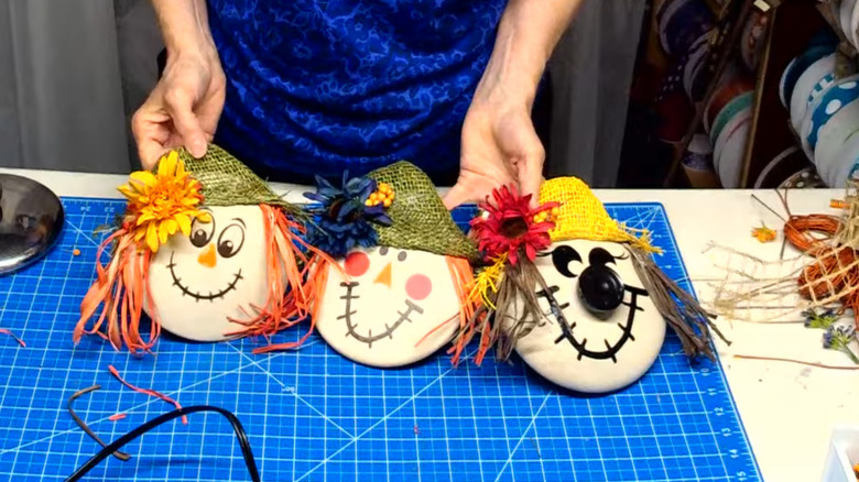 Three scarecrow heads made from pot lids