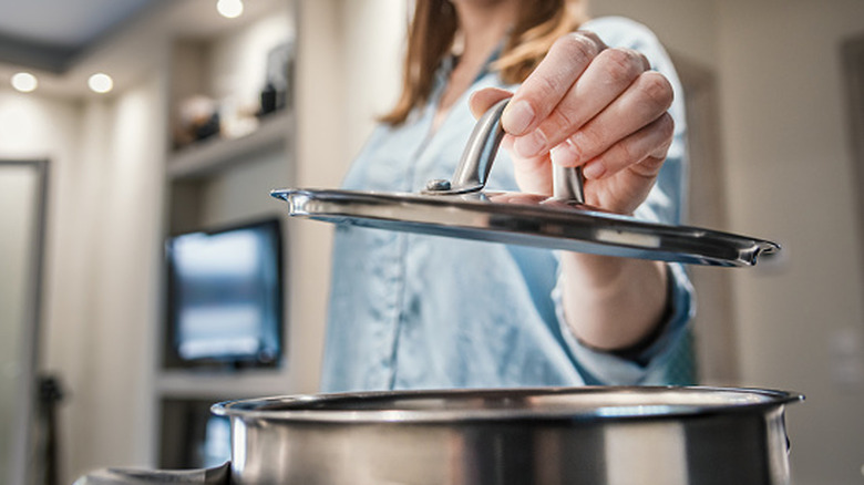 Woman lifting a lid off a pot
