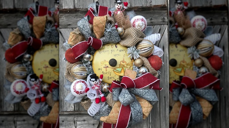 A wreath on a rough wooden door made of a pot lid and ribbons