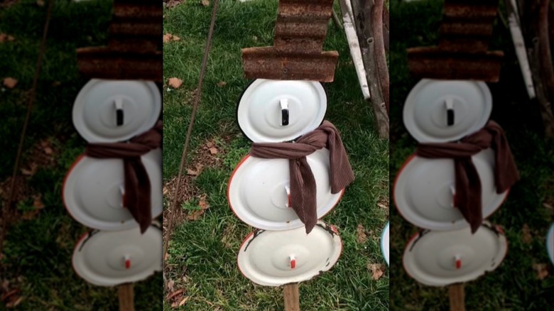 Minimalistic snowman made of pot lids on a post
