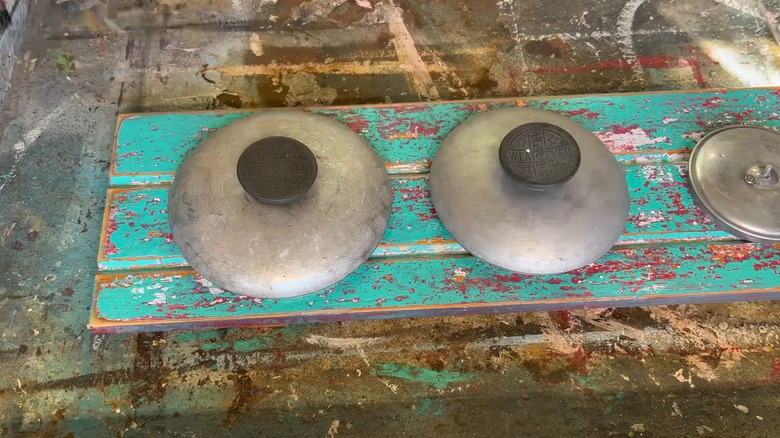 A row of metal pot lids on a wood board