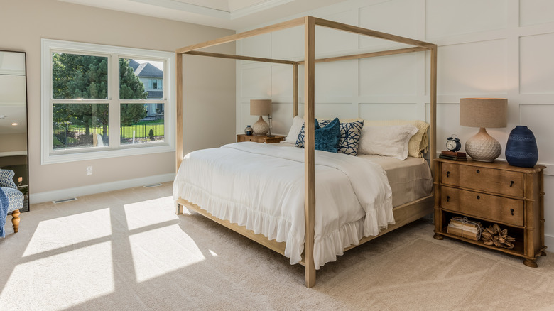 bedroom with full carpet, canopy bed, and ruffled bedding