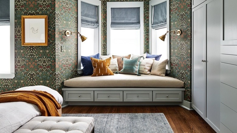 green wallpapered bedroom with bay window bench seating with pillows