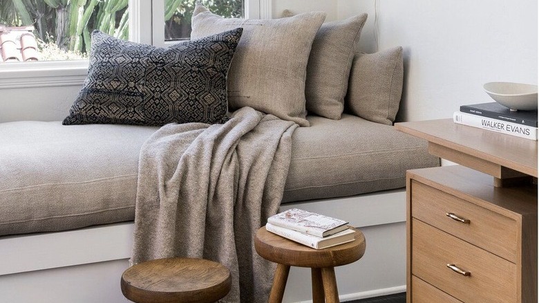 white room with gray window bench and two stools below it