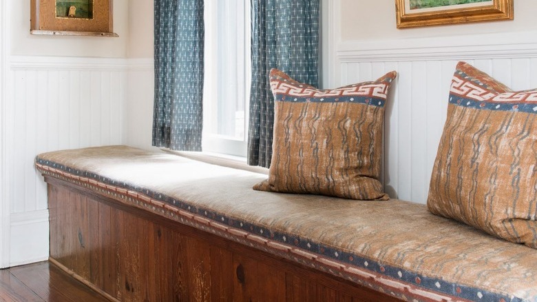 vintage window bench with curtains and wall art surrounding it