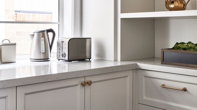white modern kitchen with green cabinetry and matching window bench