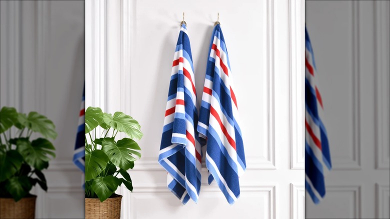 Two Loftex beach towels in red, white, and blue hang against a white wall