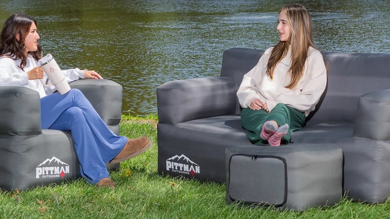 Two women sitting on a chair and couch outdoors by a pond