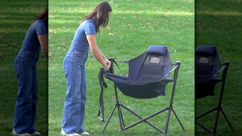 Person assembling the Tommy Bahama swinging hammock chair on a lawn
