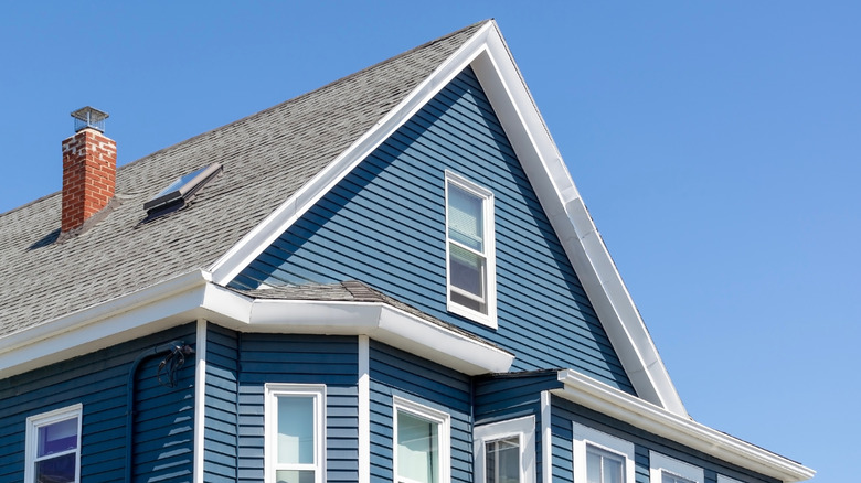exterior of a home with a gray shingled roof, medium blue siding, and white trim