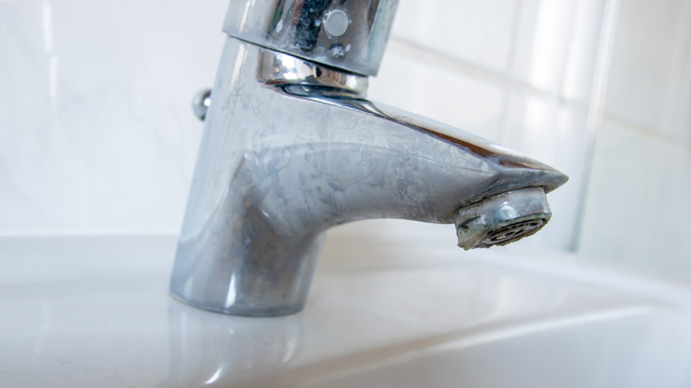 Close-up of a bathroom faucet covered in hard water stains