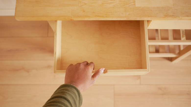 Hand opening an empty wood drawer