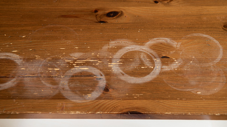 A series of water rings and damage on the surface of wood furniture