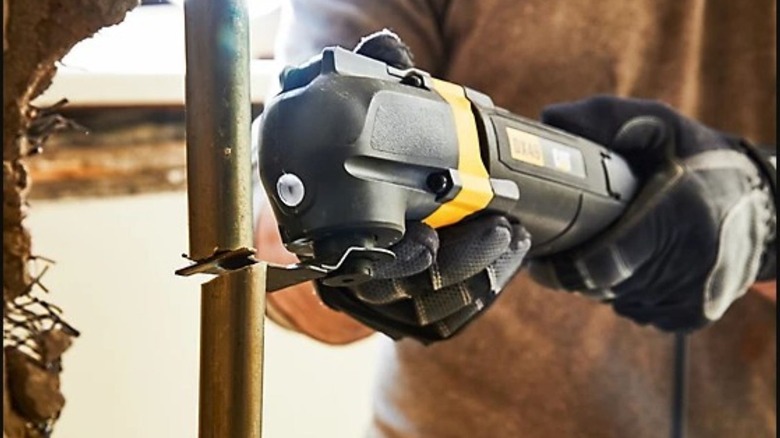 Someone cutting a pipe with the Cat oscillating multi-tool