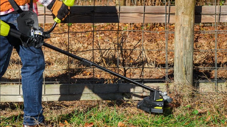 Man using the Ryobi brush cutter and string trimmer on his lawn