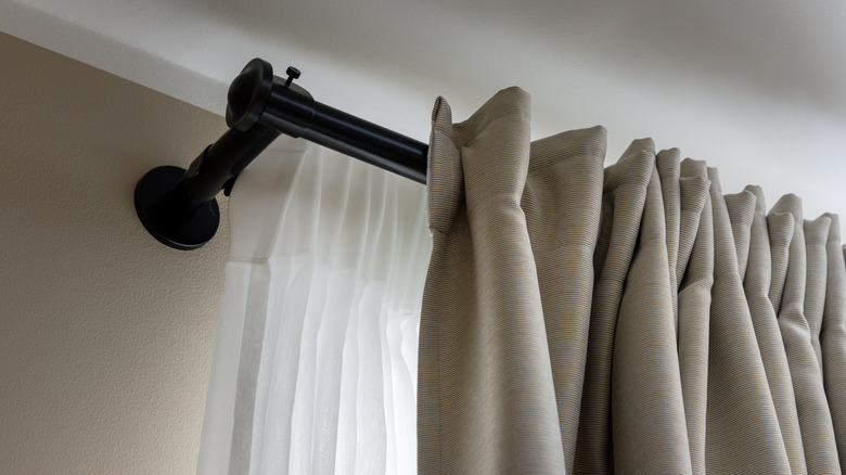 A big black curtain rod with gray curtains