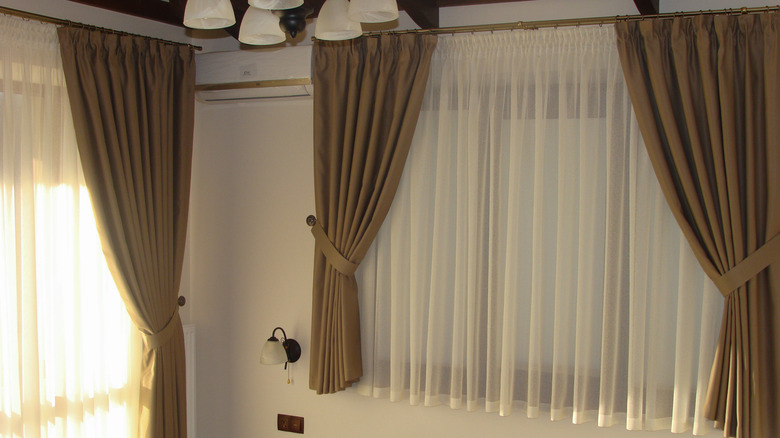 A room with two windows with the same style curtains
