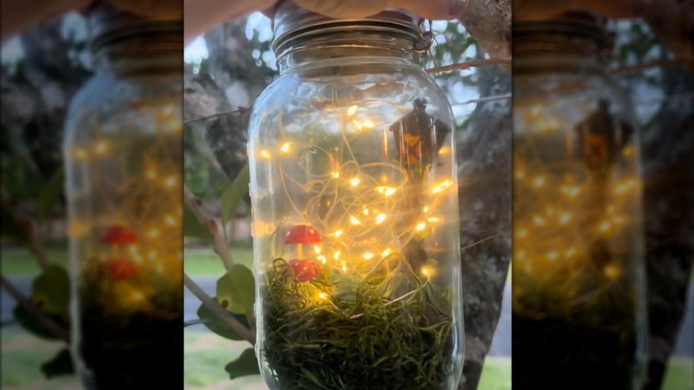 Mason jar with moss, small objects and fairy lights inside