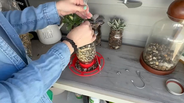 DIYer assembling a bird feeder made with a kit and a Mason jar