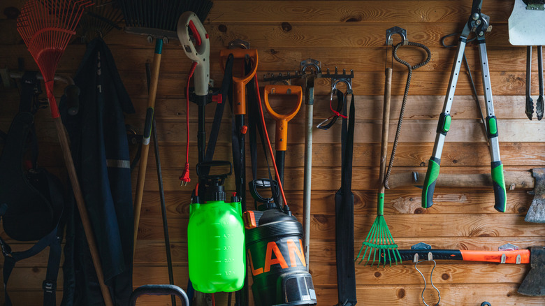 A wooden shed with gardening tools on the wall