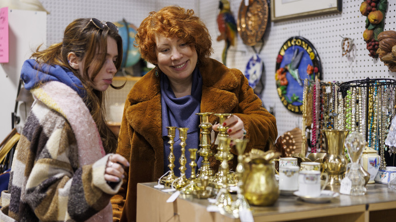 A pair of women looking at candle holders in a thrift store