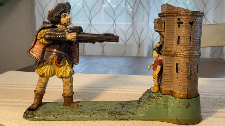 An antique metal bank featuring William Tell shooting an apple off a boy's head