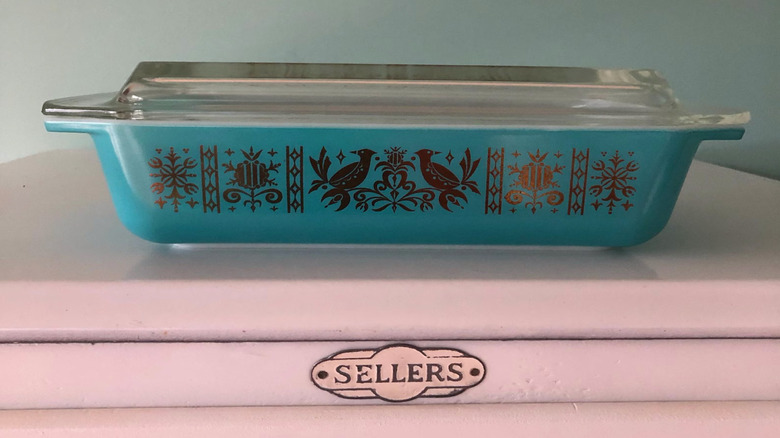 a Pyrex Turquoise Golden Birds Space Saver on a pink table