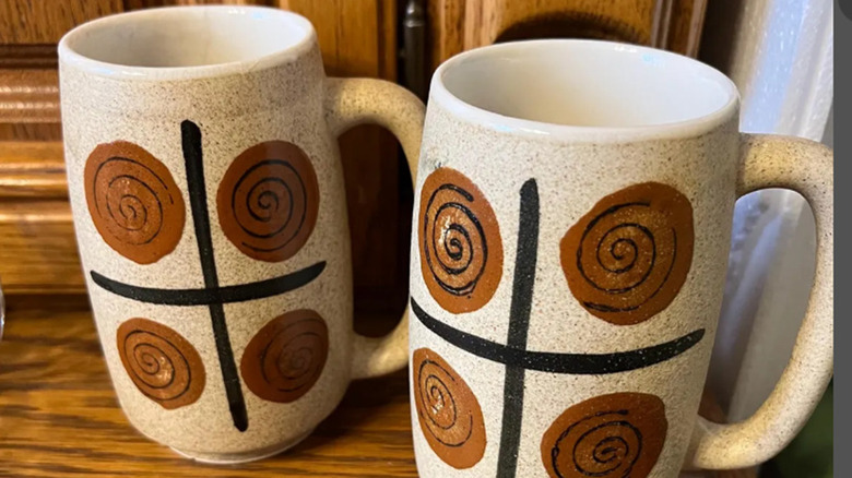A pair of Otagiri-made mugs with hand-painted brown designs.