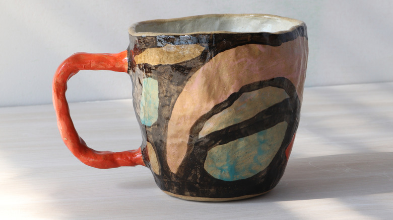 A hand-crafted and painted pottery mug with abstract design.