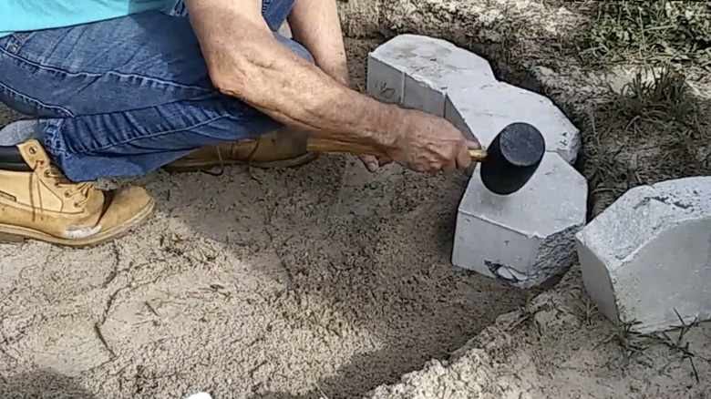 Person assembling backyard firepit with garden wall blocks
