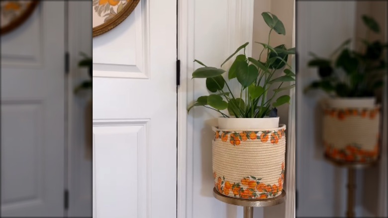 Thrifted rope basket decorated with decoupaged orange images sitting on a countertop with oranges inside