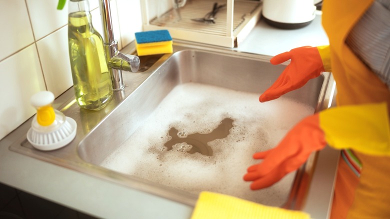 Woman standing at sink full of water