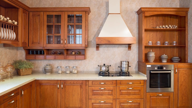 Kitchen with brightly stained wooden cabinets, with the countertop and shelves decorated with neutral and green decor